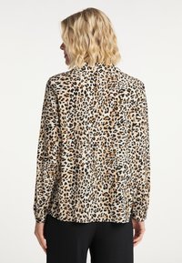 Långärmad skjorta i lätt tyg med en beige grund och svarta samt bruna leopardfläckar. Lös passform med knäppte ärmslut.
