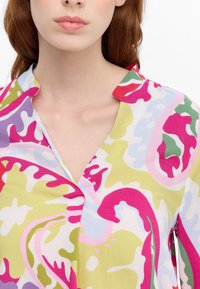 Blusa colorata con motivo astratto e scollatura a V, caratterizzata da tonalità di rosa, verde, giallo e blu in un tessuto seta.