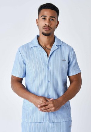 Chemise boutonnée à manches courtes bleu clair avec un motif rayé texturé, col ouvert et détail de poche avant.