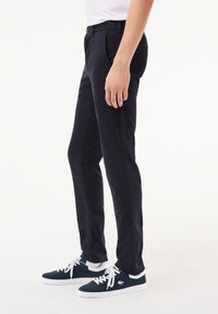 Chinos de ajuste slim en azul marino, confeccionados en una mezcla de algodón, con cierre frontal de botón, cinturilla con trabillas y sutiles bolsillos laterales.