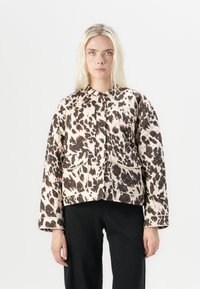 Chaqueta acolchada con un patrón abstracto en beige y marrón oscuro, con cuello redondo, dos bolsillos frontales y mangas relajadas.