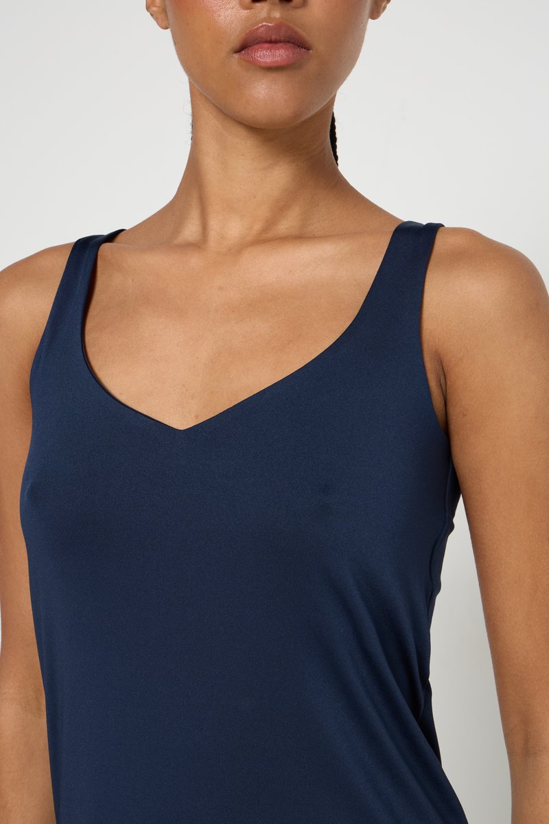 Haut sans manches bleu marine avec un décolleté en V profond et un tissu lisse et extensible. Présente une silhouette ajustée et des coutures minimales.