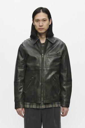 Veste en cuir noir avec une fermeture éclair à l'avant, deux poches latérales et une poche poitrine. Présente un col classique et une finition légèrement texturée.