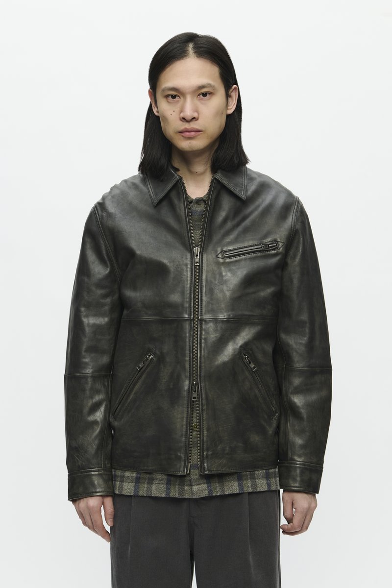 Black leather jacket with a zip front, two side pockets, and a chest pocket. Features a classic collar and slightly textured finish.