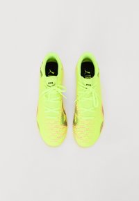 Bright yellow athletic shoes with textured patterns and black accents. Features flat laces and a cushioned collar for comfort.