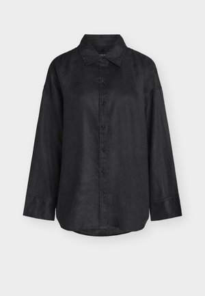 Chemise noire à manches longues avec col, coupe ample et ourlet droit, présentée sur un fond gris clair.