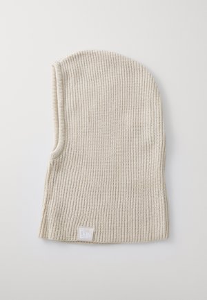 Kootud beanie heledast beežist, millel on sooniktekstuur. Hemmikul on väike valge logo silt. Ülikõrgus sobituv disain kitseneva ülaosaga.