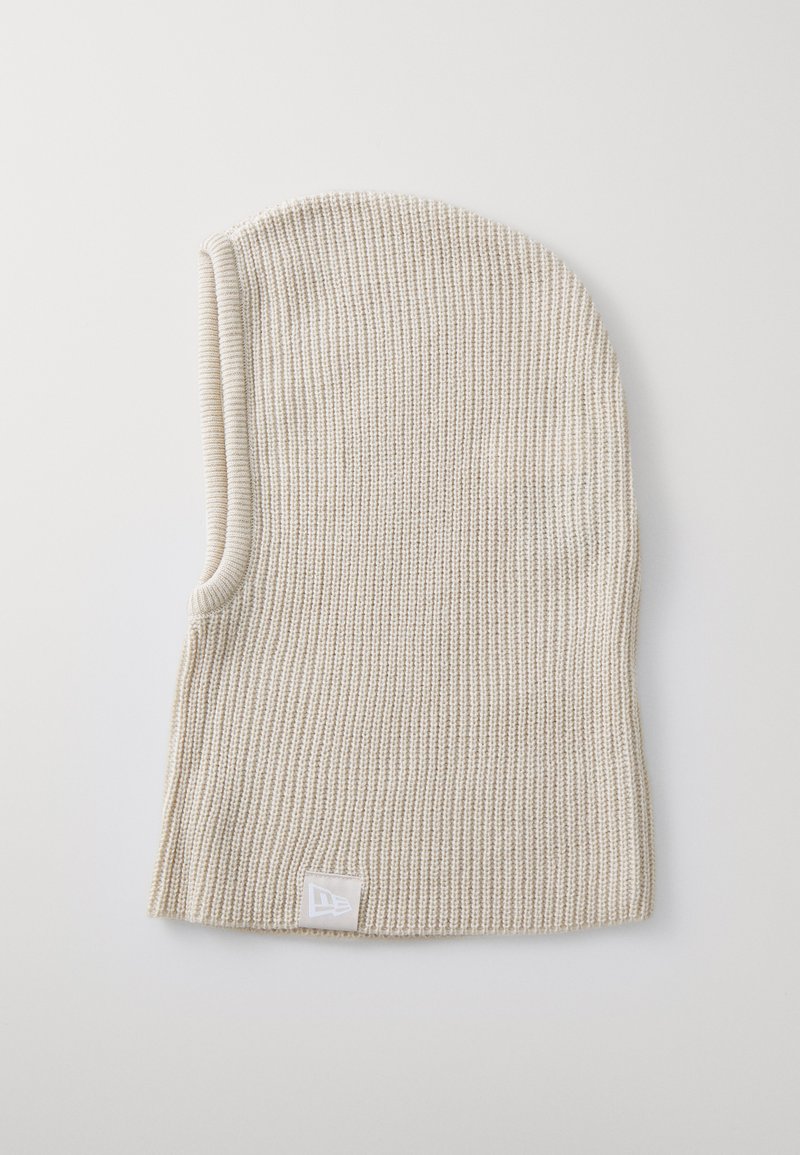 Knit beanie in light beige, featuring a ribbed texture. Includes a small, white logo patch at the hem. Form-fitting design with a tapered top.