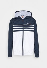 Veste coupe-vent bleu marine et blanche avec capuche, comportant trois rayures blanches horizontales sur la poitrine et une fermeture éclair sur le devant.