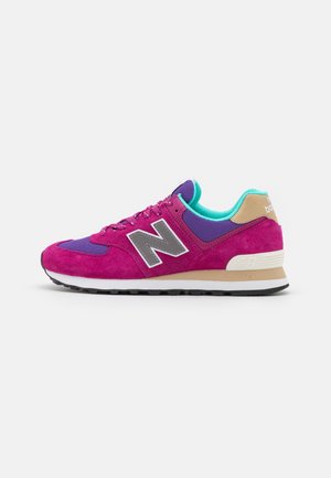 Fioletowo-różowe buty sportowe New Balance z turkusową wyściółką, beżowym detalem na pięcie, białą środkową podeszwą i czarną podeszwą zewnętrzną, pokazane z boku.