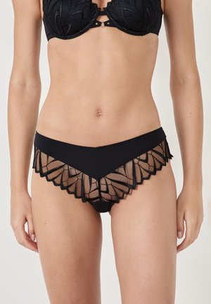 Black underwear with a scalloped lace overlay featuring geometric patterns. Made of soft fabric with a mix of opaque and sheer textures.