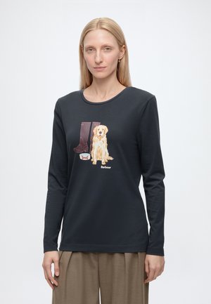 Femme portant un t-shirt noir à manches longues avec un motif de bottes marron et un chien golden retriever sur le devant.