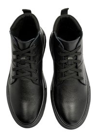 Czarne skórzane buty za kostkę z okrągłymi czubkami, teksturowanym wierzchem i czarnymi sznurowadłami. Posiadają pętelkę z tyłu dla łatwego zakładania.