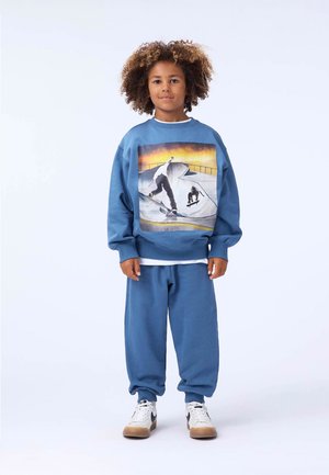 Light blue sweatshirt featuring a graphic of skateboarders, paired with matching sweatpants. The material appears soft and cozy.
