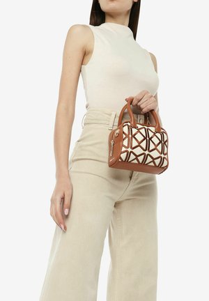 Borsa marrone con un motivo geometrico crema, dotata di manici corti e una cerniera. Il modello tiene la borsa indossando un top beige aderente e pantaloni chiari.