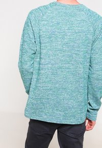 Zeleno-modrá melírovaná mikina s dlouhým rukávem, kulatým výstřihem a raglánovými rukávy; měkká textura, volný střih.