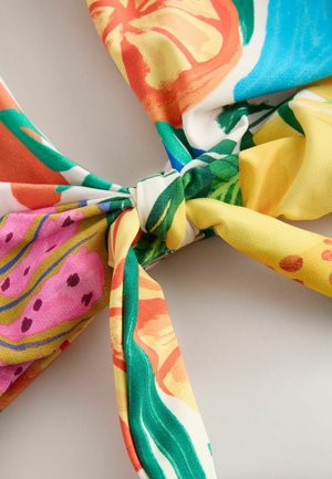 Kolorowy szal z tkaniny z kwiatowym wzorem w kolorach pomarańczowym, różowym, zielonym i żółtym. Posiada wiązany węzeł na środku, gładką fakturę.