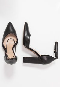 Černé lodičky s špičatou špičkou z hladké kůže. Mají kotníkový pásek a široký podpatek pro podporu. Vnitřek je béžový.