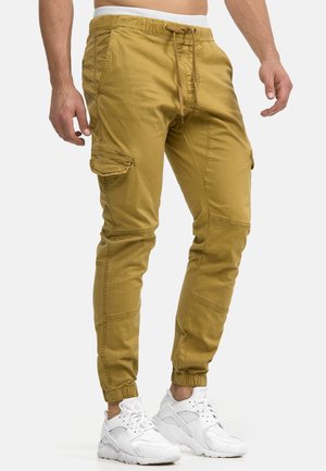 Cargo-Hosen in Khaki, aus Baumwolle, mit einem elastischen Bund, Kordelzugverschluss, seitlichen Taschen und elastischen Bündchen an den Knöcheln.