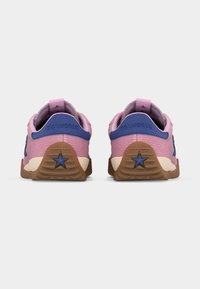 Ζευγάρι ροζ και μπλε αθλητικών παπουτσιών Converse, εμφανιζόμενα από πίσω, με καφέ σόλες και λογότυπο αστεριού στη φτέρνα.