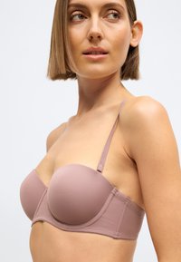 Lyse lilla, polstret, stropløs bh med glat tekstur, justerbare tynde stropper og sømløst design. Har bøjle for støtte.