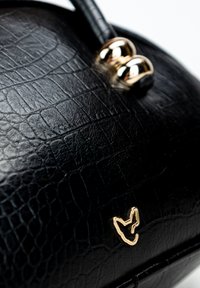 Borsa in finta pelle nera con texture a coccodrillo, dotata di hardware dorato e un emblema distintivo. Forma arrotondata con un manico corto.