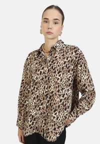 Camicia a bottoni con stampa leopardata in tonalità beige e marrone, caratterizzata da un taglio morbido, colletto e maniche lunghe con polsini abbottonati.