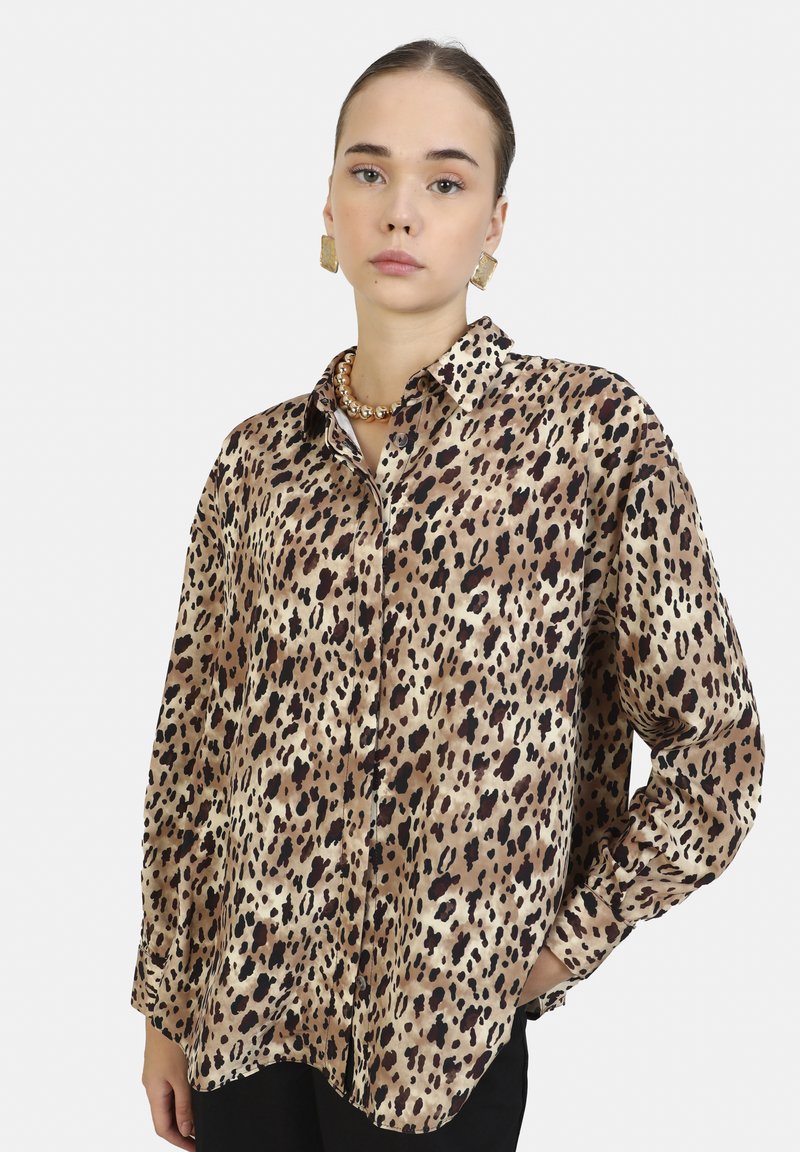 Camicia a bottoni con stampa leopardata in tonalità beige e marrone, caratterizzata da un taglio morbido, colletto e maniche lunghe con polsini abbottonati.