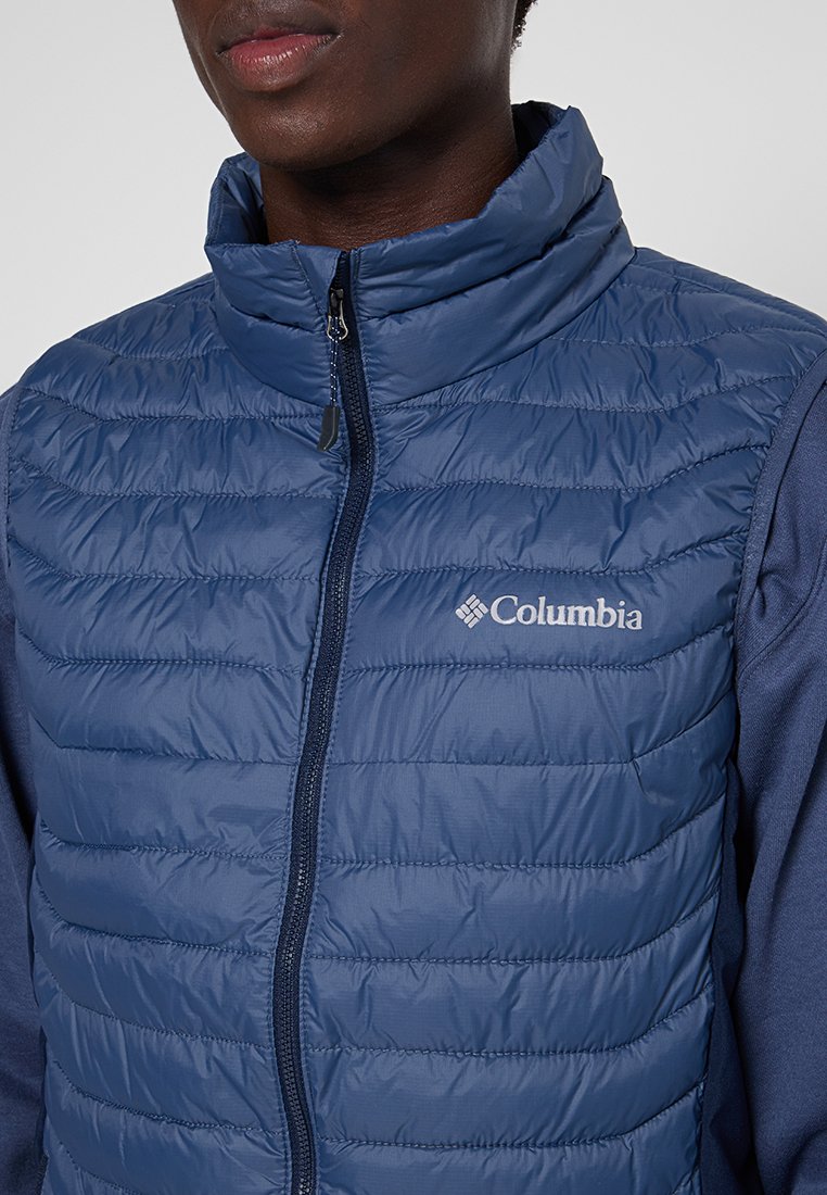 Gilet imbottito blu navy con design a righe orizzontali, colletto alto e zip frontale; presenta il logo Columbia in bianco sul lato sinistro.