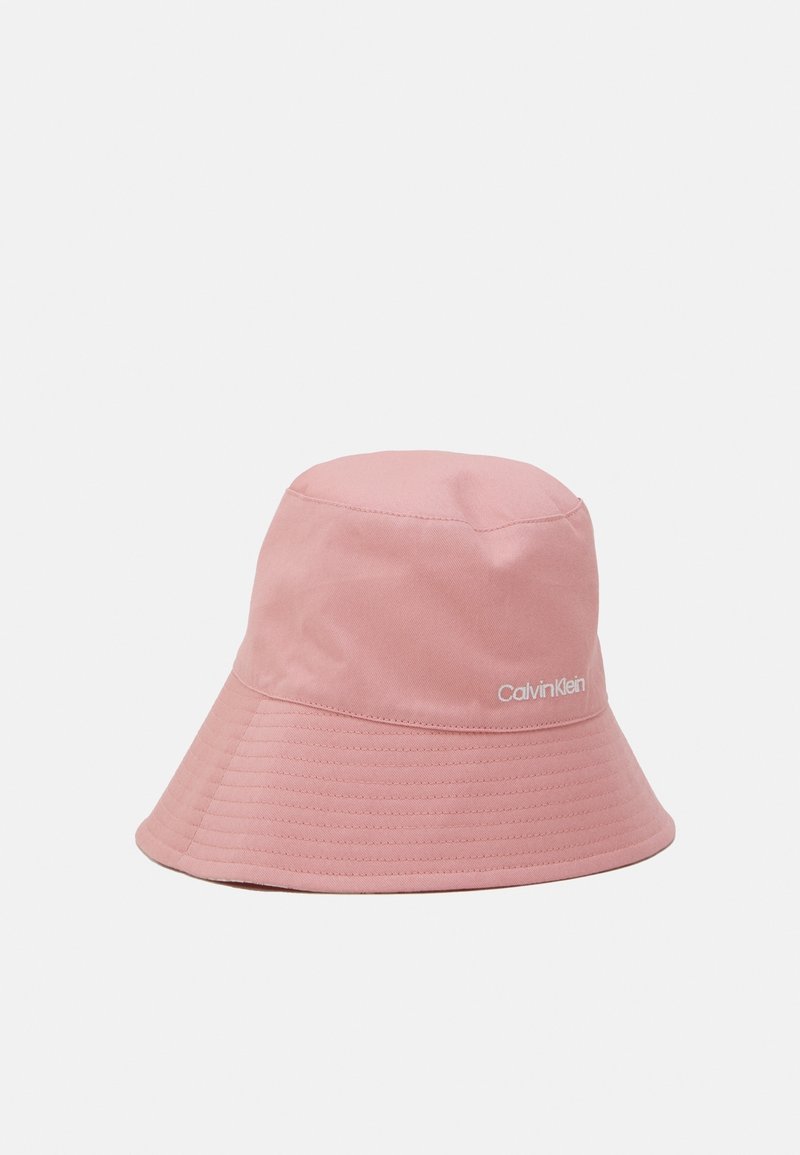Chapeau bob en tissu rose avec large bord cousu et logo blanc Calvin Klein sur le côté sur un fond clair uni.