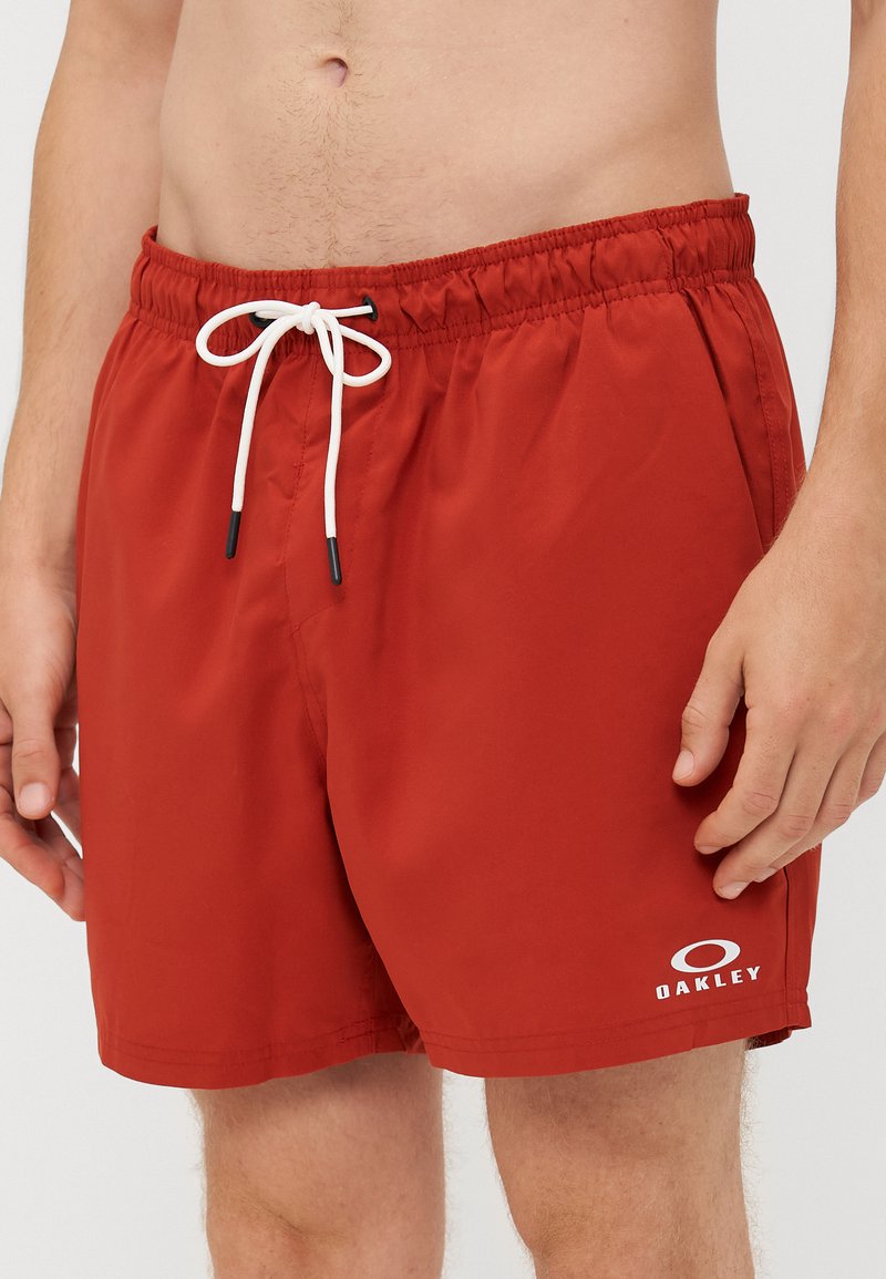 Pantaloni da bagno rossi realizzati in tessuto leggero, con cintura elasticizzata e cordino, e un piccolo logo bianco sull'orlo.