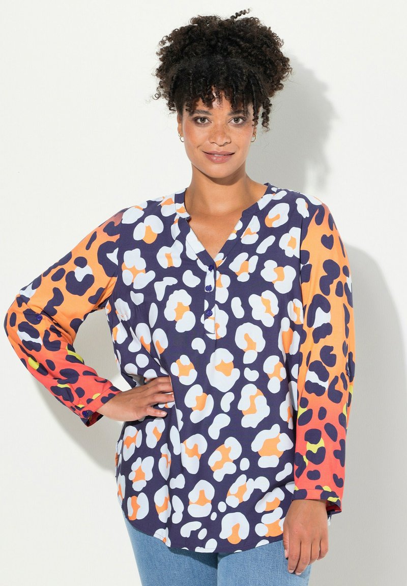 Blusa multicolore con una base blu navy e motivi astratti bianchi, arancioni e viola; maniche lunghe con dettaglio a bottone.