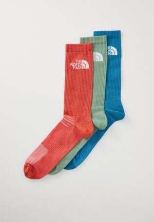 Three pairs of knee-length socks in red, green, and blue; ribbed texture; white logo on each sock; reinforced heel and toe.