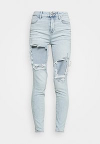 Ljusblå skinny jeans med slitna detaljer och stora hål runt knäna. Klassisk femfickorsdesign, tillverkade av denimtyg.