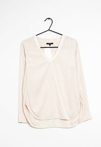 Blusa de manga larga, de color beis claro, con escote en V, sutileces laterales y un solo bolsillo en el pecho. Fabricada con una tela suave y ligera.