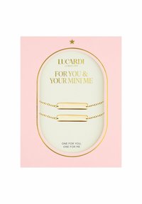 Gouden armbanden met gladde, uitgerekte staven, geplaatst op delicate kettingen. Gepresenteerd in een roze en gouden doos met tekst.