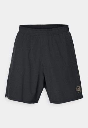 Black athletic shorts made from lightweight fabric, featuring an elastic waistband and a gold circular logo on the lower right side.