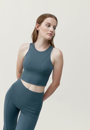 Harmaa urheilu toppi pyöreällä kaula-aukolla ja tiukalla muotoilulla, yhdistettynä matching korkeavyötäröisiin leggingseihin, joissa on sauman yksityiskohtia.