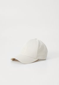 Lys beige baseballcap lavet af blødt stof, med et forhøjet emblem på fronten, buet skygge og seks-panel design.