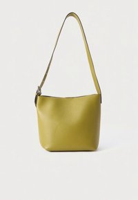 Kožená kabelka v barvě hořčice, měkká textura, zakřivený tvar, jeden nastavitelný popruh, minimalistický design, žádné viditelné kovové doplňky.