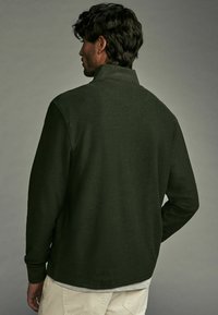 Dunkelgrüner Pullover aus strukturierter Stoffqualität, mit hochgeschlossenem Kragen und langen Ärmeln. Verfügt über einen lässigen Schnitt und ein schlichtes Design.