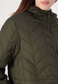 Olive green insulated jacket with a hood, featuring a quilted diamond pattern and a front zipper. Material appears smooth and durable.