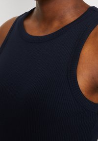 Žebrovaný námořnický tank top s kulatým výstřihem a širokými průramky, vyrobený z měkké, elastické látky pro příjemné a přiléhavé nošení.