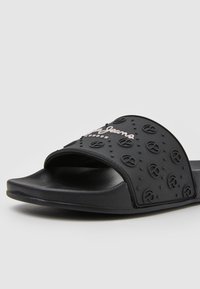 Sandale noire à bout ouvert avec une sangle texturée présentant des motifs de logo circulaires et le nom de la marque "Pepe Jeans London" en relief.