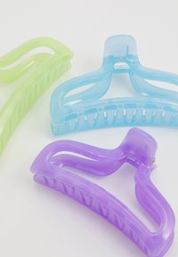 Três presilhas de cabelo de plástico nas cores verde, azul e roxo. Cada uma tem um acabamento suave, um design curvado e dentes entrelaçados para maior aderência.