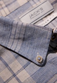 Camicia a scacchi blu e bianca con colletto, tessuto testurizzato e dettagli con bottoni. L'etichetta recita "JACK'S REGULAR FIT."