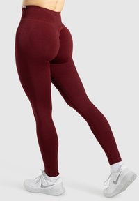 Leggings borgogna a vita alta realizzati in tessuto elastico, con silhouette aderente, texture liscia, dettagli con cuciture sul retro e sui lati.