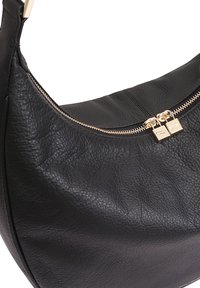 Sac à main en cuir noir avec une surface texturée, une forme incurvée et des détails de fermeture éclair dorés en haut. Comprend des tirettes de fermeture éclair doubles.