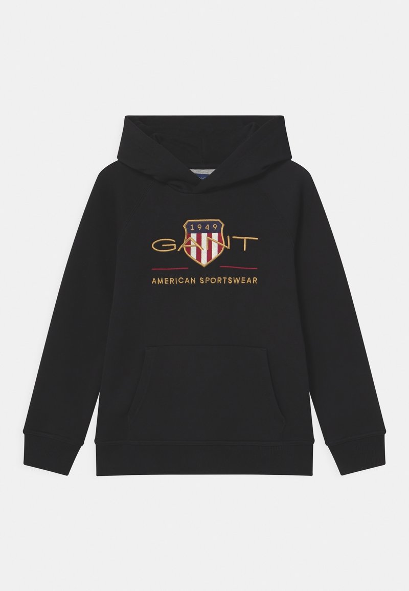 Sudadera negra con capucha y bolsillo delantero tipo canguro, con un logo bordado de un escudo con franjas rojas y blancas y texto dorado. Textura suave.