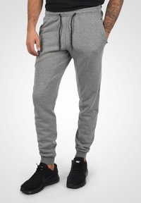 Grå bomuldsjoggers med elastisk talje og snor, der har sidelommer og ribbede manchetter, sammen med sorte sportssko.
